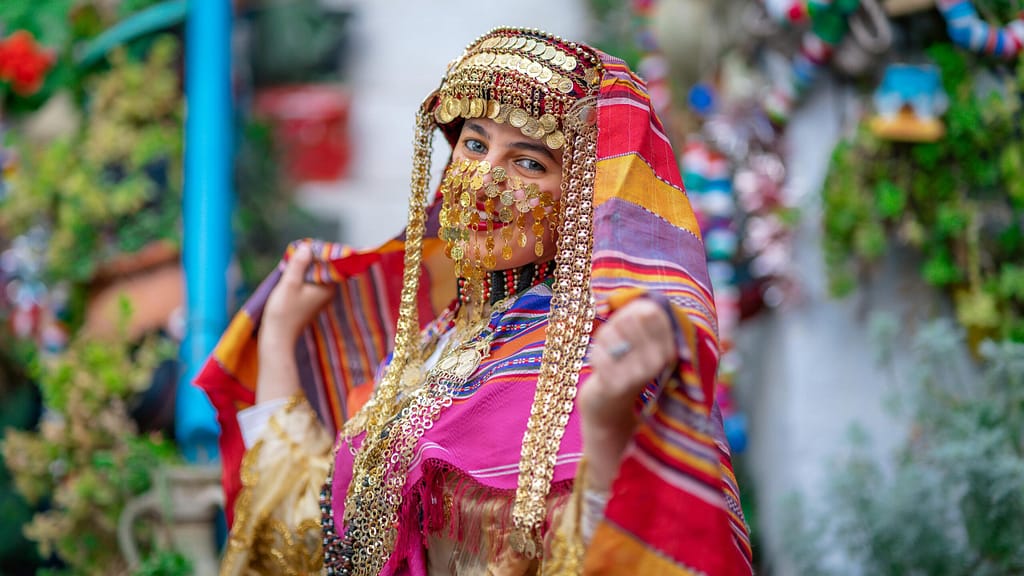 A woman in vibrant traditional Tunisian clothing posing in Hammamet, Tunisia.