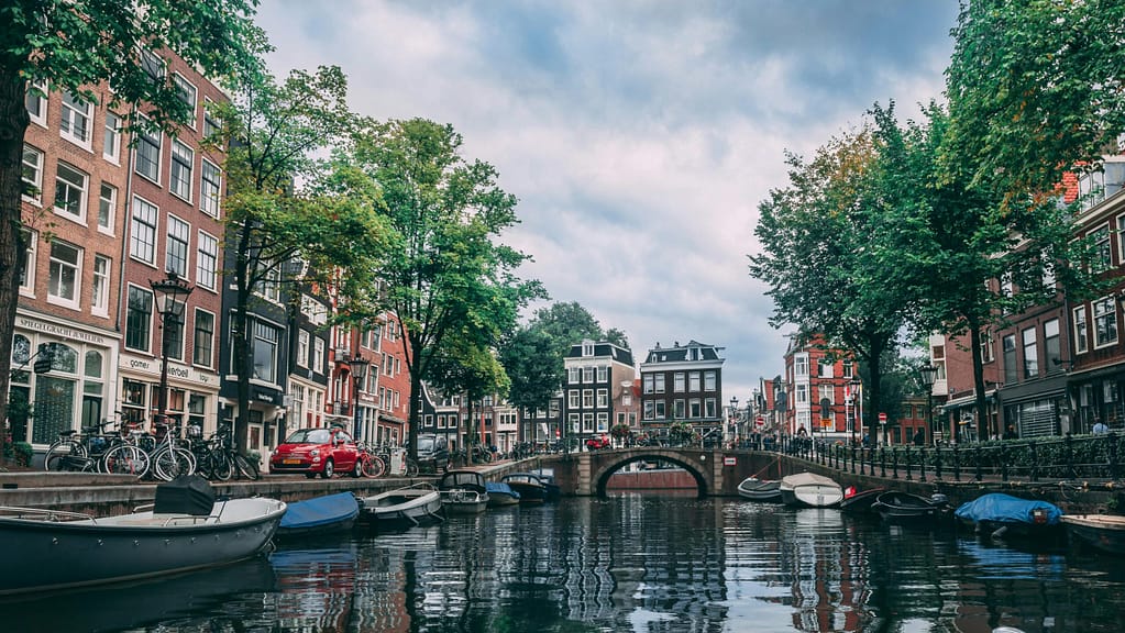 Charming view of an Amsterdam canal lined with bicycles, boats, and historic buildings.