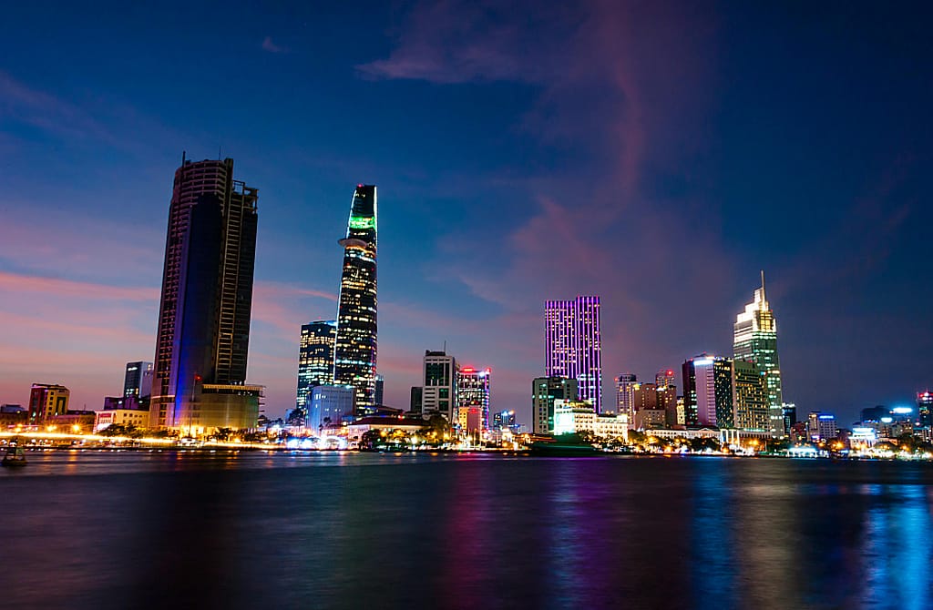 A stunning evening view of Ho Chi Minh City's skyline reflecting vibrant lights over the Saigon River.