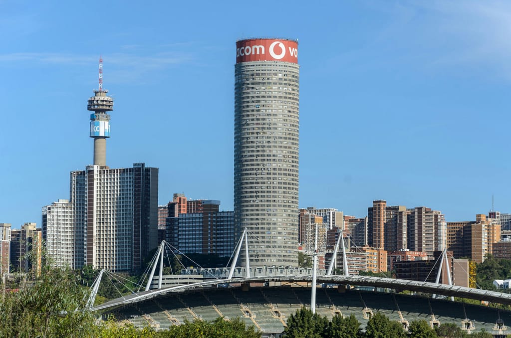 Skyline view of Johannesburg with iconic Ponte Tower under a blue sky.
