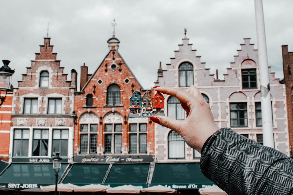 pexels-photo-2634202-2634202 A hand holding a miniature Bruges building with traditional Belgian architecture in the background.