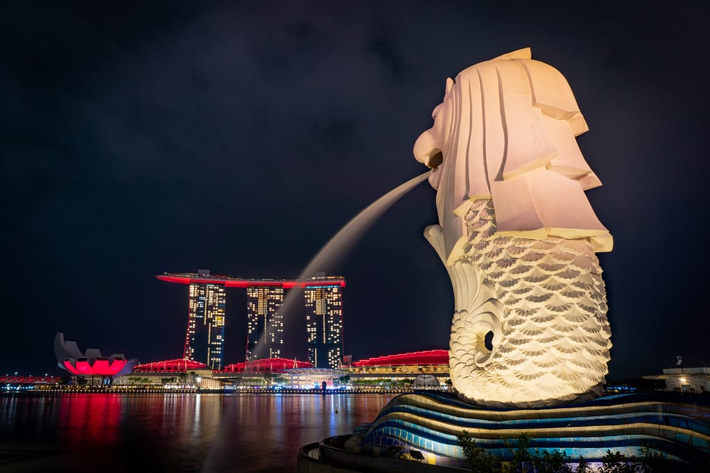 Night view of the iconic Merlion statue with Marina Bay Sands illuminated in Singapore.