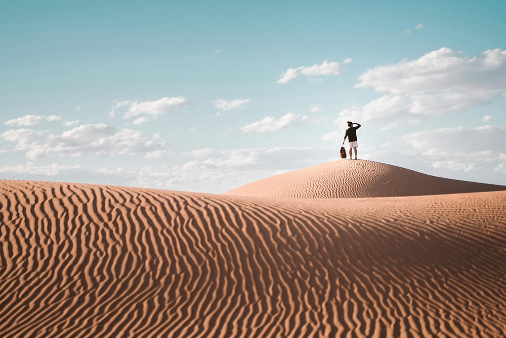 A lone traveler atop a sand dune in Al Wahat Al Dakhla Desert, Egypt.