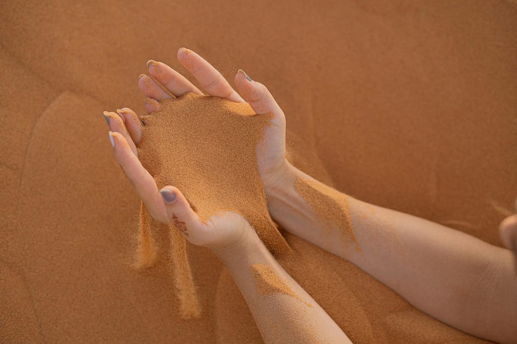 Close-up of hands letting sand flow in the Merzouga Desert, Morocco
