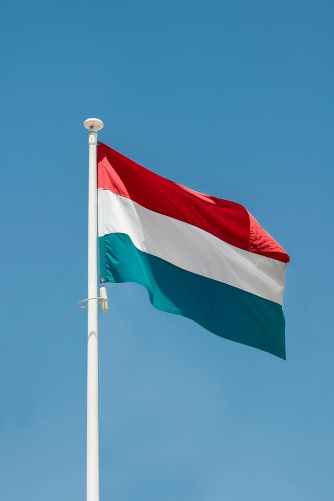 Luxembourg national flag wavers majestically against a clear blue sky, symbolizing national pride.