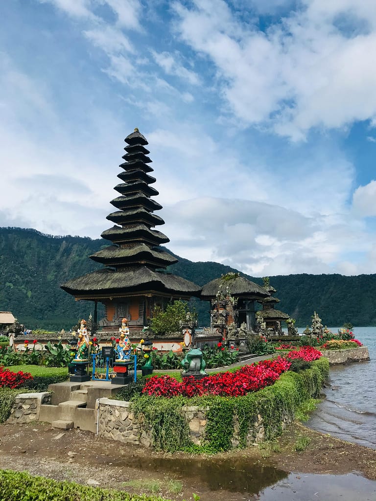 Peaceful view of a Balinese temple by the lake under a blue sky.