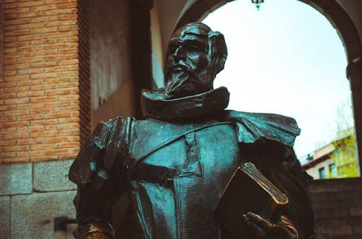 Bronze statue depicting Don Quixote, set under an archway in Toledo, Spain.